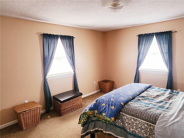 bedroom featuring carpet floors, a textured ceiling, and multiple windows