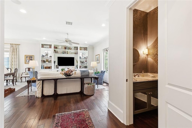 living room with crown molding, ceiling fan, dark hardwood / wood-style flooring, and built in features