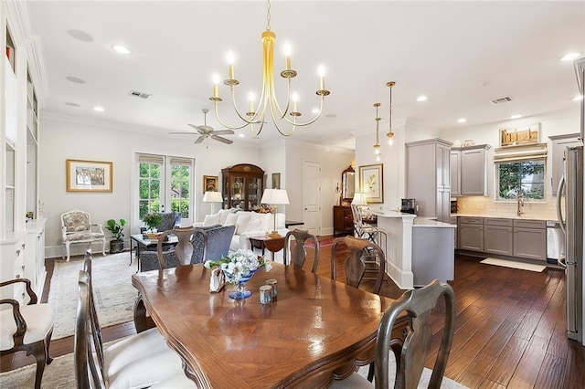 dining space with dark hardwood / wood-style flooring, crown molding, and ceiling fan with notable chandelier