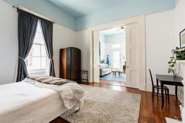 bedroom with dark hardwood / wood-style floors and multiple windows