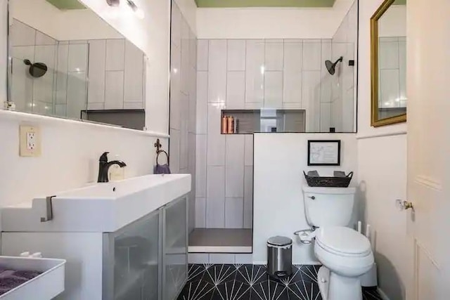 bathroom featuring tiled shower, tile patterned floors, vanity, and toilet