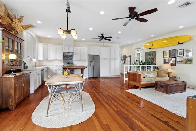 kitchen featuring white cabinetry, sink, stainless steel appliances, pendant lighting, and wood-type flooring