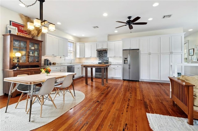 kitchen featuring ceiling fan, stainless steel appliances, tasteful backsplash, dark hardwood / wood-style flooring, and white cabinets