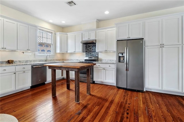 kitchen with stainless steel appliances, white cabinetry, dark wood-type flooring, and light stone counters