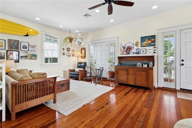 living room featuring ceiling fan and dark hardwood / wood-style floors