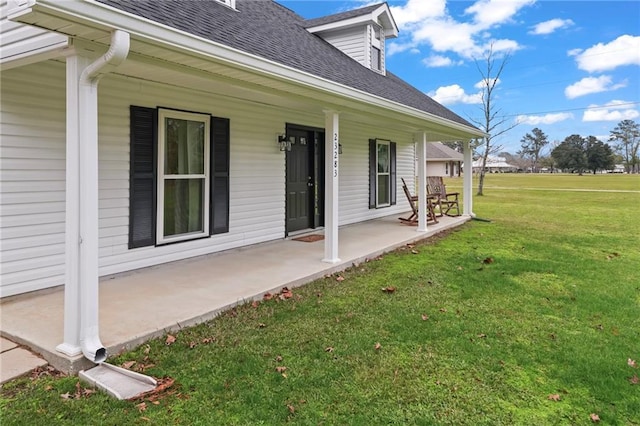 doorway to property featuring covered porch and a yard