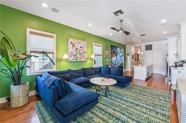 living room with hardwood / wood-style flooring, ceiling fan, and sink