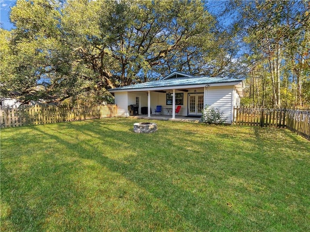 back of property with a yard, an outdoor fire pit, a patio, and french doors