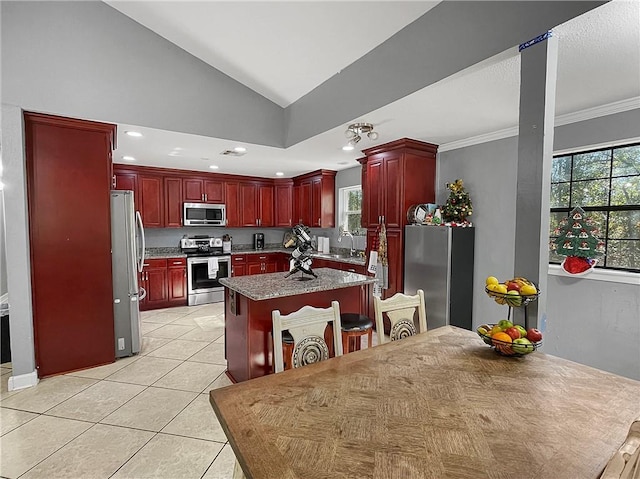 kitchen with sink, stainless steel appliances, lofted ceiling, light tile patterned floors, and ornamental molding