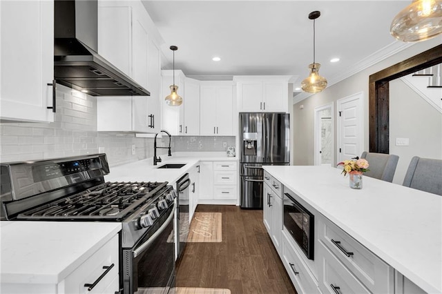 kitchen with pendant lighting, white cabinetry, sink, black appliances, and wall chimney range hood