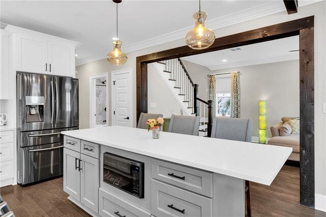 kitchen featuring stainless steel refrigerator with ice dispenser, decorative light fixtures, a center island, black microwave, and white cabinets