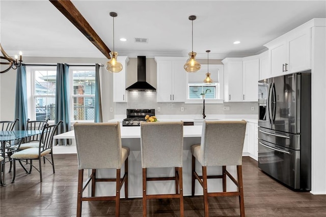 1508 N Roman St, New Orleans, LA 70116 - kitchen with wall chimney range hood, stove, light countertops, and stainless steel fridge