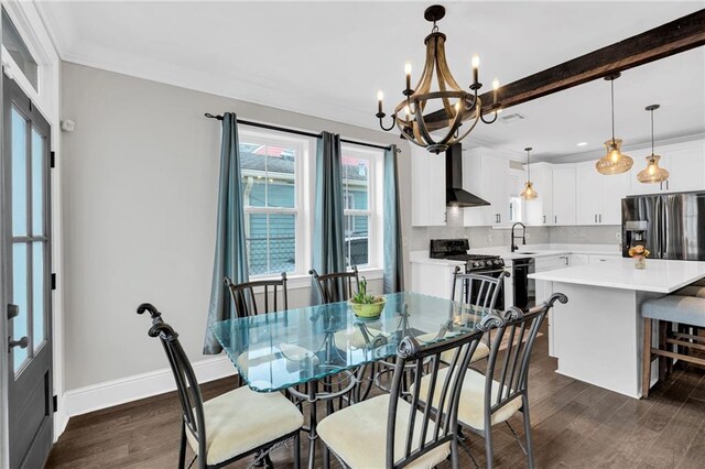 dining area with dark wood-type flooring, an inviting chandelier, crown molding, and sink