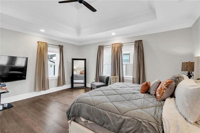 bedroom with a raised ceiling, crown molding, dark hardwood / wood-style floors, and ceiling fan