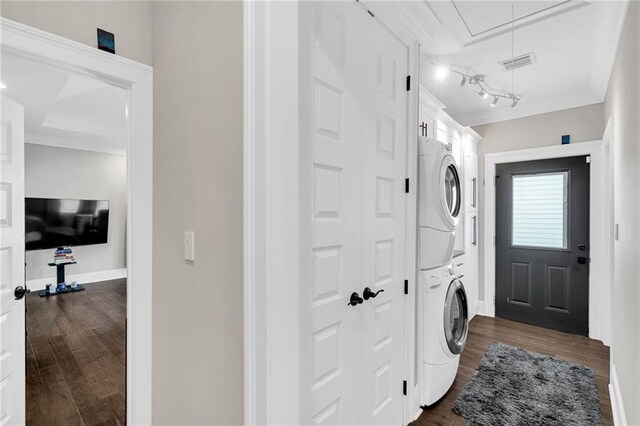 laundry room with dark hardwood / wood-style floors, track lighting, ornamental molding, and stacked washer and clothes dryer