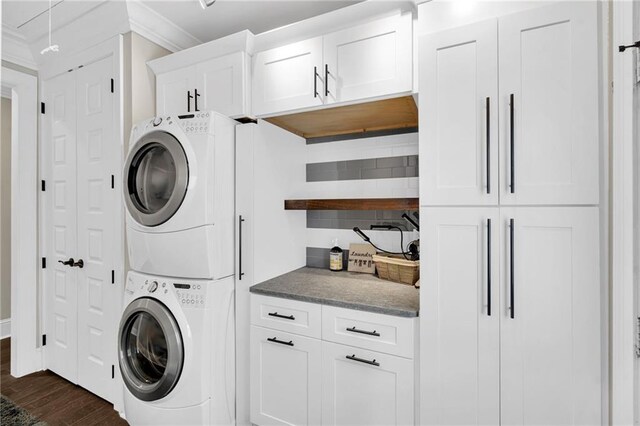 laundry room with cabinets, stacked washer / drying machine, and dark hardwood / wood-style flooring