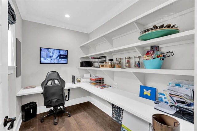 office space with dark wood-type flooring, ornamental molding, and built in desk