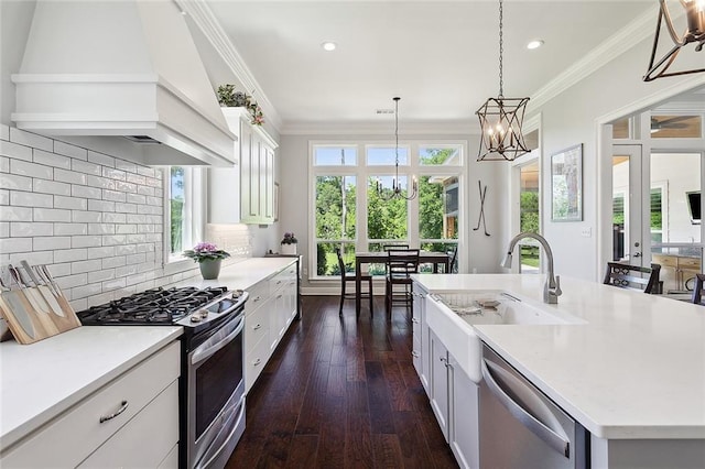 kitchen featuring sink, stainless steel appliances, pendant lighting, a kitchen island with sink, and custom exhaust hood