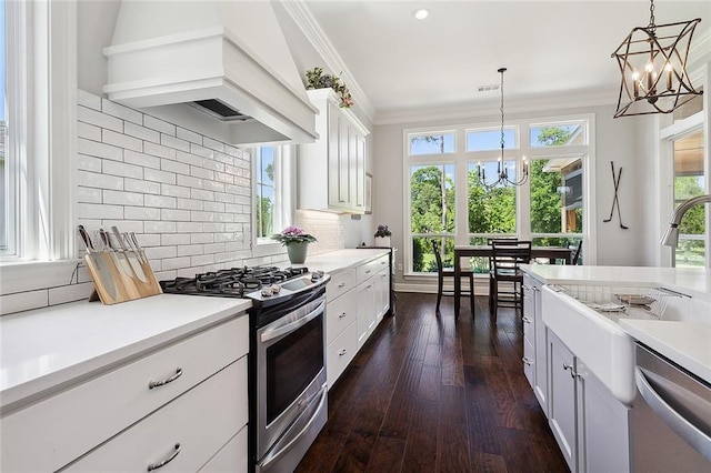 kitchen featuring appliances with stainless steel finishes, premium range hood, an inviting chandelier, and decorative light fixtures