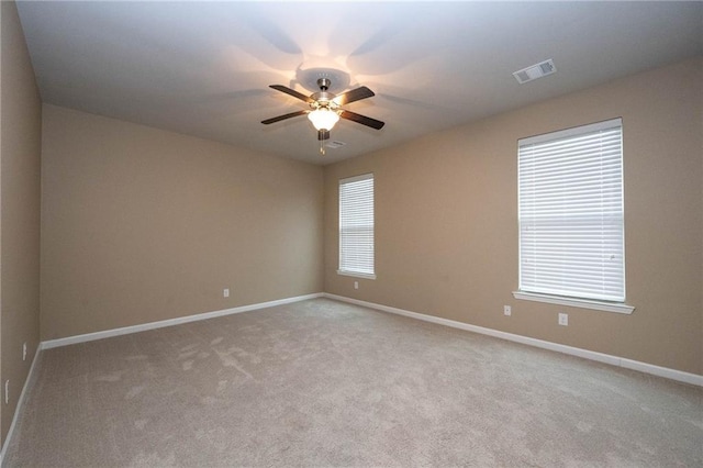 carpeted empty room featuring a wealth of natural light and ceiling fan