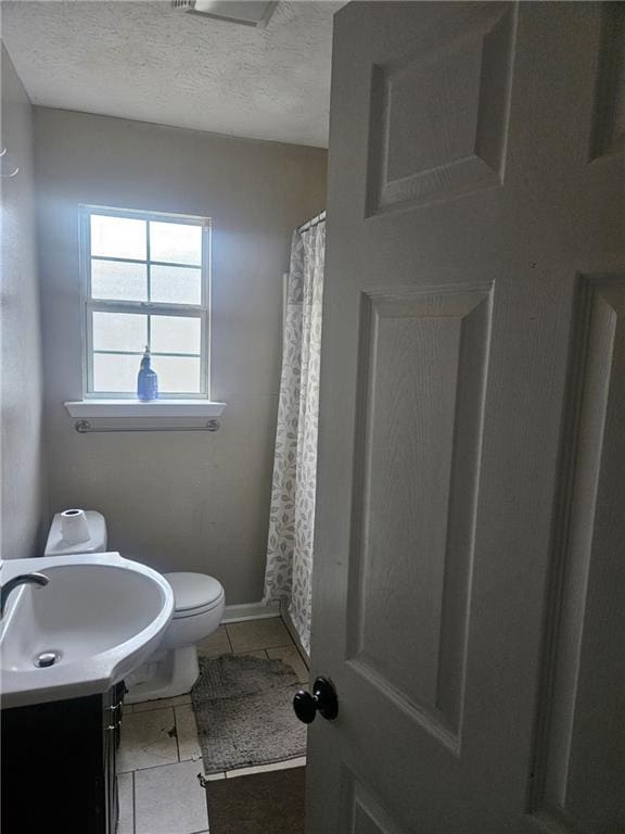 bathroom featuring tile patterned flooring, vanity, a textured ceiling, and toilet