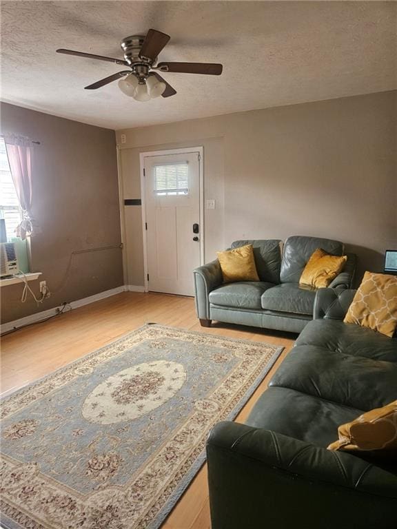 living room with ceiling fan, light hardwood / wood-style floors, and a textured ceiling