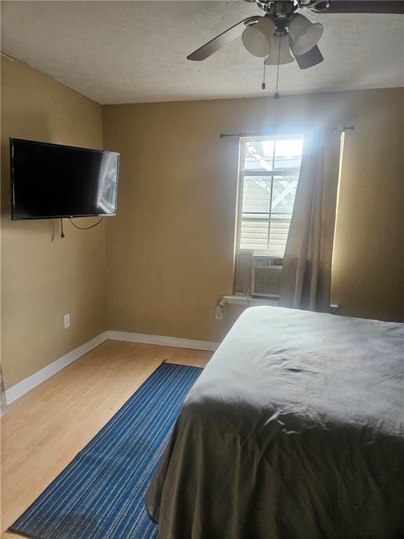 bedroom with cooling unit, wood-type flooring, and ceiling fan