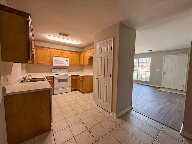 kitchen featuring white appliances, sink, and light tile patterned floors