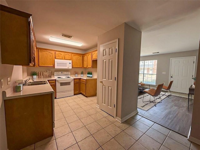 kitchen featuring light tile patterned flooring, white appliances, and sink