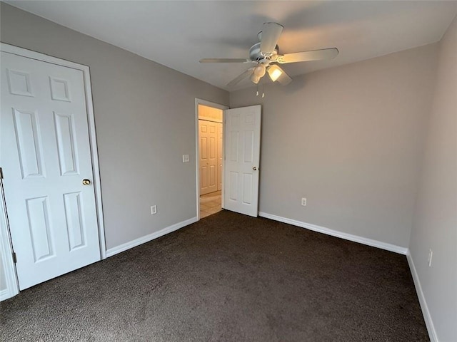 unfurnished bedroom featuring ceiling fan and dark colored carpet