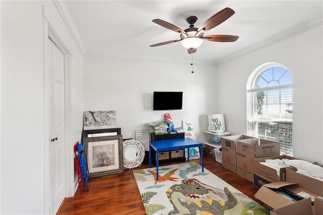 game room with a textured ceiling, ceiling fan, dark hardwood / wood-style flooring, and crown molding