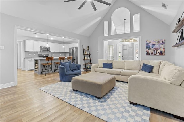 living room featuring ceiling fan, high vaulted ceiling, and light wood-type flooring