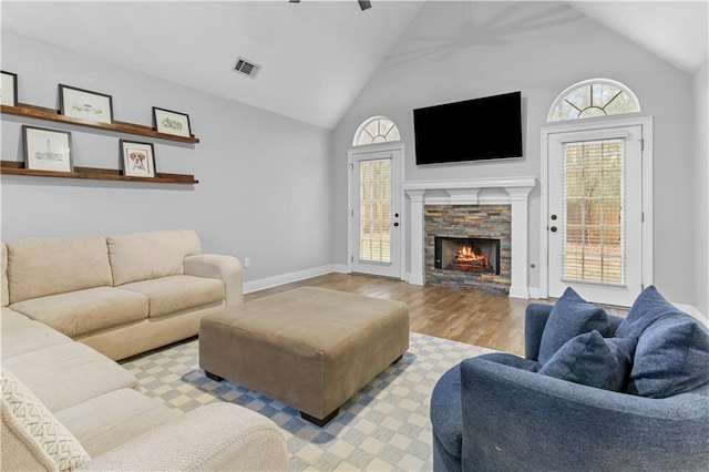 living room with a fireplace, light hardwood / wood-style flooring, ceiling fan, and a healthy amount of sunlight