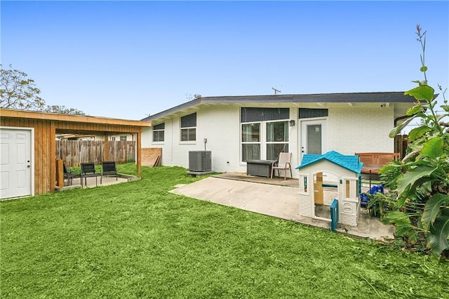 rear view of property with a yard, central AC unit, and a patio area