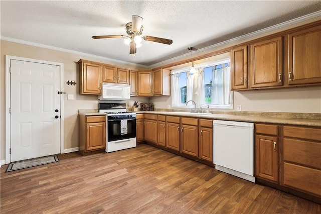 kitchen with white appliances, ceiling fan, crown molding, sink, and pendant lighting