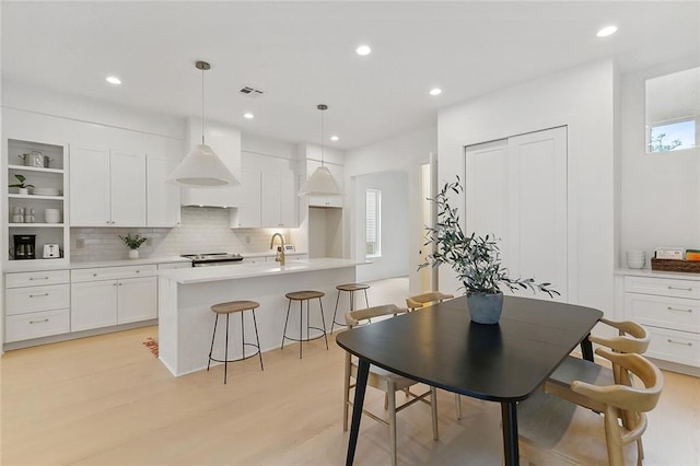 kitchen with pendant lighting, light hardwood / wood-style floors, and white cabinets