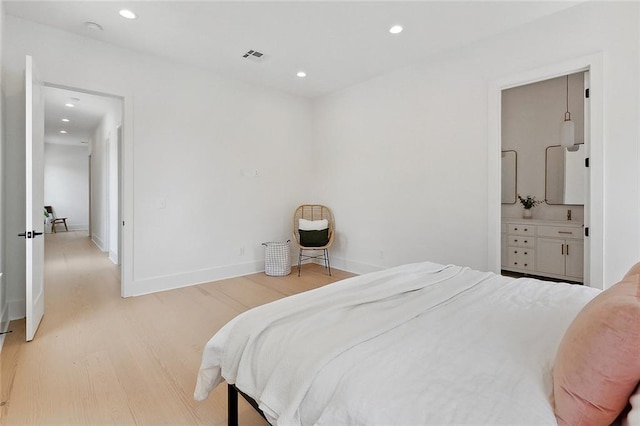 bedroom with light hardwood / wood-style floors and connected bathroom