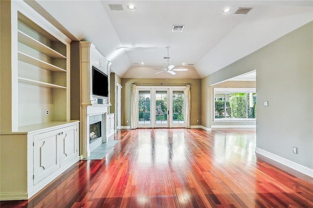 unfurnished living room with built in shelves, ceiling fan, dark hardwood / wood-style flooring, lofted ceiling, and a fireplace