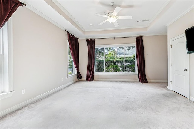 empty room featuring ceiling fan, carpet floors, a raised ceiling, baseboards, and ornamental molding