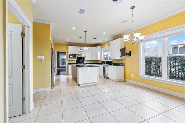 kitchen featuring a center island, hanging light fixtures, ornamental molding, appliances with stainless steel finishes, and white cabinetry