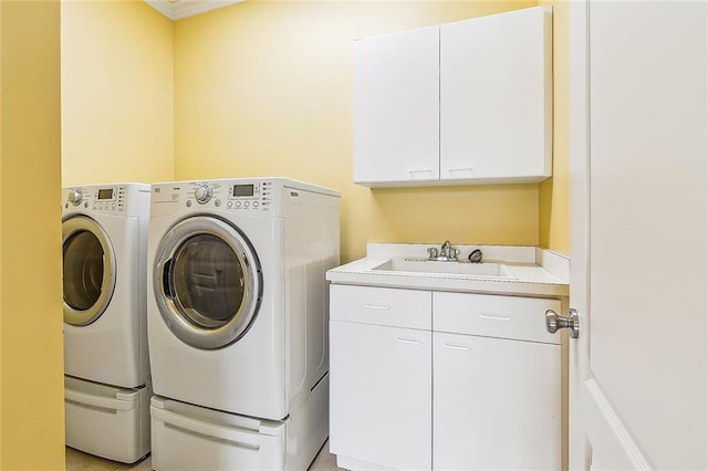 laundry area with cabinet space, washing machine and clothes dryer, and a sink