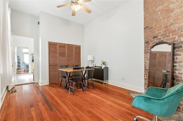 dining room featuring a high ceiling, hardwood / wood-style flooring, and ceiling fan