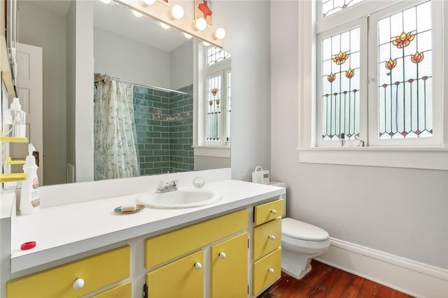 bathroom with walk in shower, hardwood / wood-style flooring, vanity, and toilet