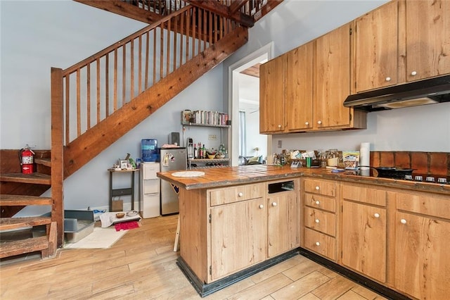 kitchen with gas cooktop, stainless steel fridge, light wood-type flooring, and kitchen peninsula