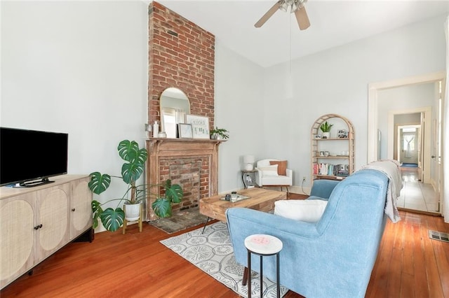 living room featuring a fireplace, hardwood / wood-style flooring, and ceiling fan