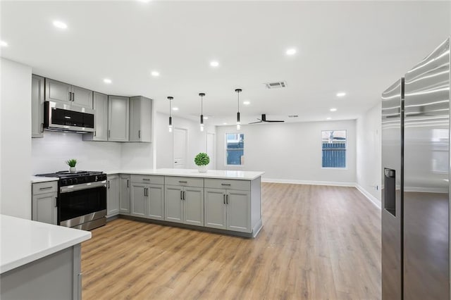 kitchen featuring gray cabinetry, hanging light fixtures, ceiling fan, kitchen peninsula, and stainless steel appliances