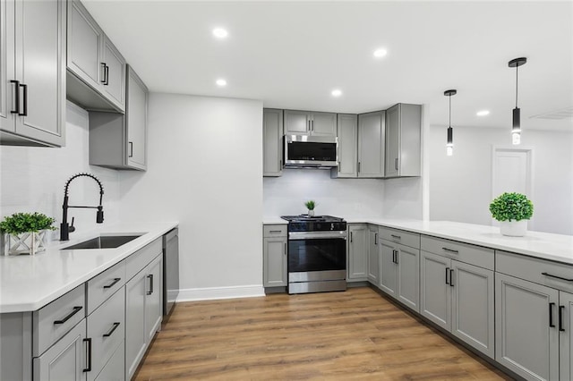 kitchen with gray cabinetry, light hardwood / wood-style floors, sink, and appliances with stainless steel finishes