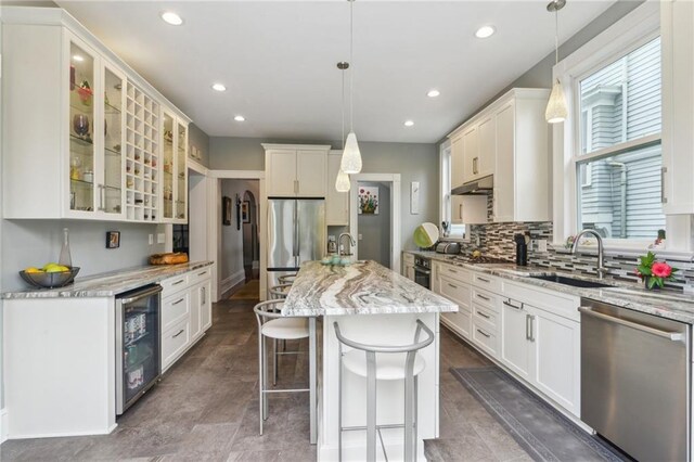 kitchen featuring appliances with stainless steel finishes, beverage cooler, hanging light fixtures, and sink