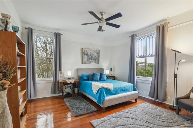 bedroom featuring ceiling fan, multiple windows, and dark hardwood / wood-style floors