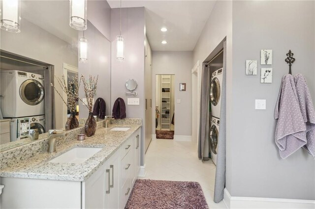 bathroom with stacked washer / drying machine, vanity, and tile patterned flooring